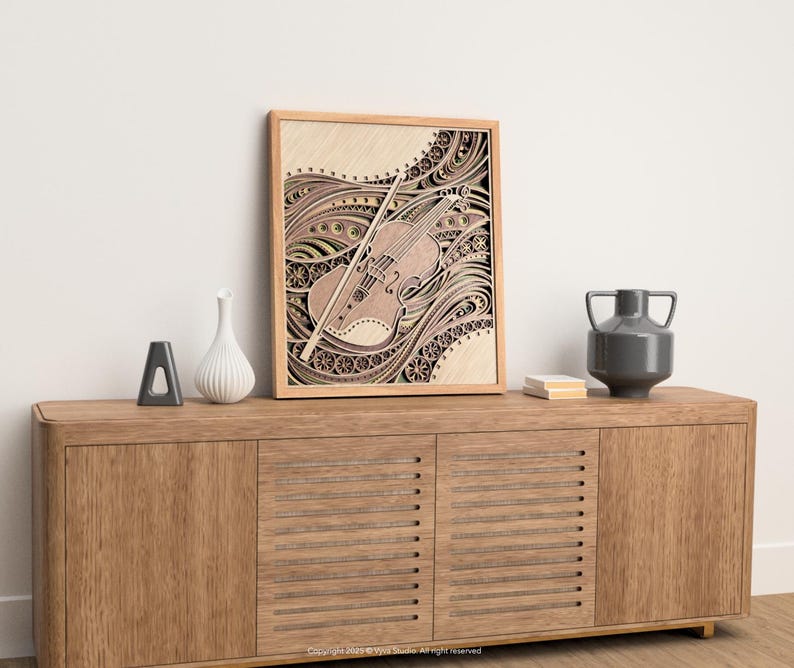 May include: A framed wooden art piece featuring a detailed violin design with a bow. The artwork is in shades of brown and beige, with intricate patterns. The piece is displayed on a wooden cabinet with decorative items.