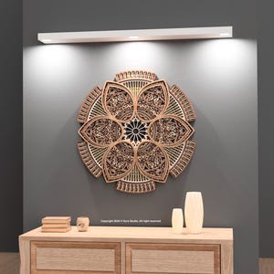 May include: A detailed wooden wall art piece in a floral design. The artwork is made of layered wood, with an intricate pattern. The piece is mounted on a grey wall above a wooden cabinet with decorative items.