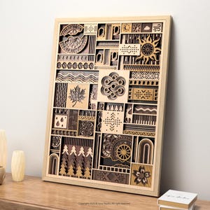 May include: Wooden wall art with a geometric design. The artwork features various shapes and patterns, including a sun, maple leaf, and trees. The piece is framed in a light-colored wood and is displayed on a wooden surface.