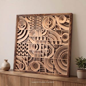 Peut inclure: Une grande œuvre d'art murale carrée en bois avec un design géométrique. L'œuvre présente des formes sculptées en couches, notamment des cercles, des demi-cercles et des rectangles. Le cadre est marron foncé, et l'œuvre est exposée sur un meuble en bois avec un petit vase et une plante en pot.