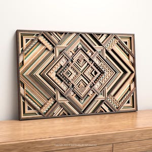 May include: Geometric wooden wall art with a layered design. The artwork features a complex pattern of squares and diamonds in shades of brown, beige, and green. The piece is framed in a dark brown border and rests on a wooden surface.