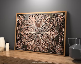 May include: A framed, layered wooden artwork with a floral pattern. The piece features a detailed, multi-layered design in shades of brown, beige, and black, set within a natural wood frame. It is displayed on a wooden surface.