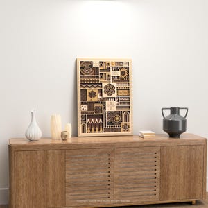 May include: A wooden framed art piece with a geometric design, displayed on a wooden cabinet. The artwork features various shapes and patterns in shades of brown and beige. Decorative vases and a dark gray vase are also on the cabinet.