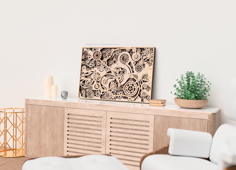 May include: A wooden wall art piece featuring a complex design of interlocking gears and mechanical elements. The artwork is displayed on a light-colored wooden cabinet, with a small plant and decorative items nearby. The overall aesthetic is modern and artistic.