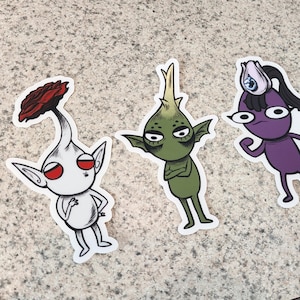 May include: Three cartoon stickers of quirky characters. One is white with a red flower head, another is green with crossed arms, and the last is purple with a long black ponytail. Each has a white border.