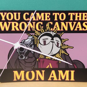 Op de afbeelding: Een rechthoekige sticker met de tekst "YOU CAME TO THE WRONG CANVAS" in gele letters op een zwarte achtergrond. De afbeelding toont een stripfiguur met een pistool, met de tekst "MON AMI" onderaan.