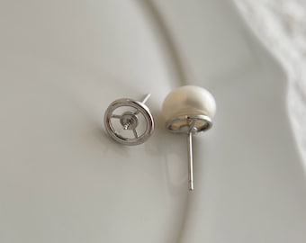 May include: A pair of silver stud earrings with a white pearl on each earring.