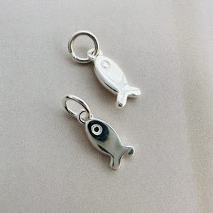 May include: Two silver fish charms with a loop for attaching to a necklace or bracelet.