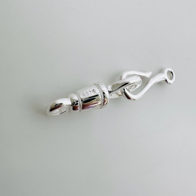 May include: Silver clasp with a hook closure and a barrel-shaped piece marked with the number "S925".