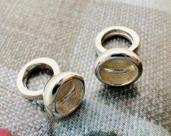 May include: Two silver-colored cufflinks with a rounded, oval design. Each cufflink has a circular ring attached to an oval-shaped face. The oval face has a recessed, textured interior. The cufflinks are displayed on a patterned surface.
