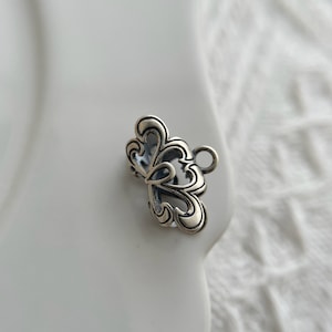 May include: Silver butterfly charm with an intricate design and a loop for attaching to a necklace or bracelet.