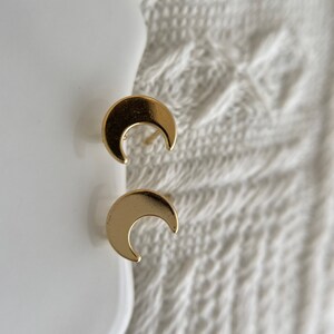 May include: A pair of gold crescent moon earrings. The earrings are small and delicate, and they would make a great gift for someone who loves celestial jewelry.