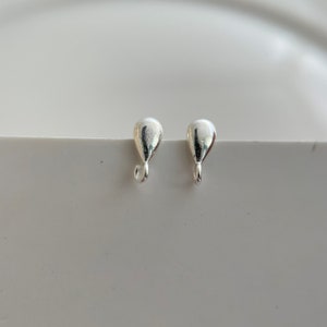 May include: Two silver teardrop-shaped earring closures with a small loop at the bottom.