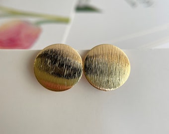 May include: A pair of gold-toned round earrings with a brushed finish.