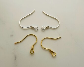 May include: Four earring hooks, two silver-colored and two gold-colored, are displayed against a white background. The hooks are curved with a looped end, designed for securing earrings. The silver hooks are bright, while the gold hooks have a warm, metallic sheen.