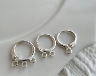 May include: Three silver earring findings with three jump rings on each. The findings are circular and have a hinged opening.