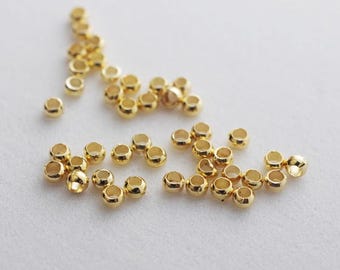 May include: A large quantity of gold-coloured metal jump rings. The jump rings are small and round, and they are scattered on a white surface.