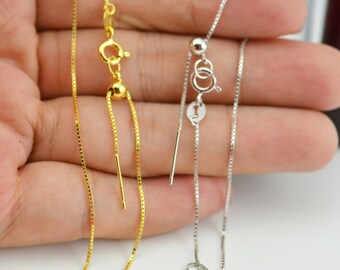 May include: Two adjustable chain necklaces, one gold and one silver, with a sliding clasp. The necklaces are made of a delicate box chain style.