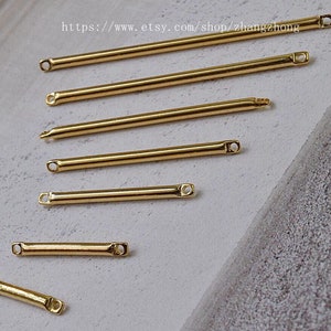 May include: Six gold metal connector bars of varying lengths, with rounded ends. The bars are arranged in a staggered pattern on a light grey surface.