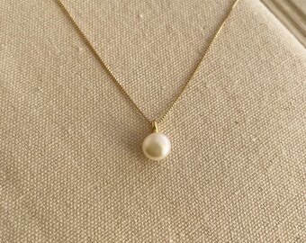 May include: A delicate gold chain necklace with a single white pearl pendant.