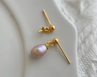 May include: A pair of gold earrings with a single pink pearl drop on one earring.
