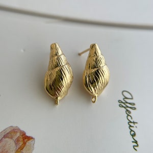 May include: A pair of gold-tone shell-shaped earrings with a textured surface.