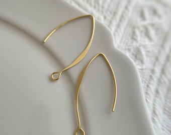 May include: Two gold-toned earring hooks with a flat, slightly curved design. The hooks are made of metal and have a smooth finish.
