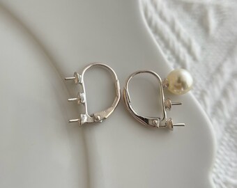 May include: A pair of silver earring findings with a single pearl attached to one of the findings.