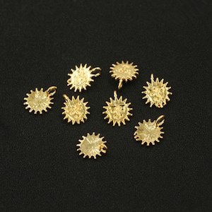 Könnte beinhalten: Acht goldfarbene Sonnen-Anhänger mit einer Öse zum Anbringen an Schmuck oder andere Bastelarbeiten.