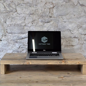 May include: A wooden laptop stand with a laptop on top. The laptop screen displays the logo "COTTAGE TWO".