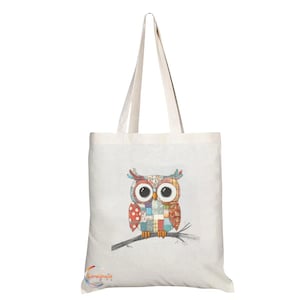May include: A cream-coloured tote bag with a colourful owl design. The owl, made from patchwork patterns in red, orange, blue, and green, sits on a branch. The bag has long handles for carrying.