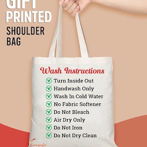 Puede incluir: Bolso de hombro de lona blanco con marcas de verificaci&oacute;n verdes y el texto "Wash Instructions" seguido de una lista de instrucciones de cuidado: Turn Inside Out, Handwash Only, Wash In Cold Water, No Fabric Softener, Do Not Bleach, Air Dry Only, Do Not Iron, Do Not Dry Clean.