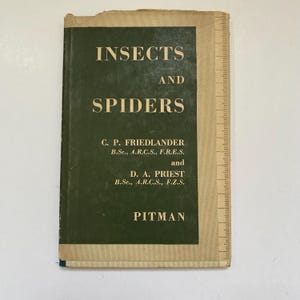 May include: An old book, "INSECTS AND SPIDERS", with a dark green cover and a beige spine. The title is in white capital letters. The authors' names and the publisher "PITMAN" are also printed on the cover.