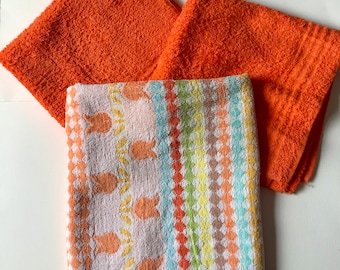 May include: Three towels, one with a colorful striped pattern and two solid orange towels.