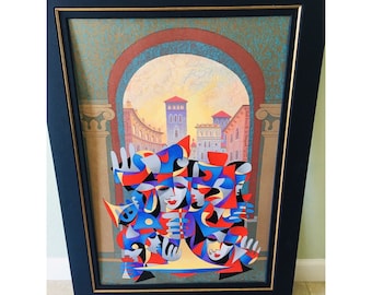 May include: Abstract art print in a black frame with a gold inner border. The artwork features a colorful, geometric design of faces and shapes in red, blue, and yellow, set against a backdrop of a European cityscape.