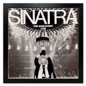 Peut inclure: Photographie en noir et blanc de Frank Sinatra se produisant en direct au Madison Square Garden à New York le 18 octobre 1974. La photo est signée par Sinatra avec une dédicace à Lynn et Body. Le texte "The Main Event Live" est imprimé au-dessus de la tête de Sinatra.