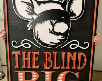 Könnte beinhalten: Ein Holzschild mit schwarzem Hintergrund und orangefarbenem Rand. Das Schild zeigt ein Cartoon-Schwein mit einem schwarzen Augenklappen und dem Text "The Blind Pig Speakeasy Lounge".