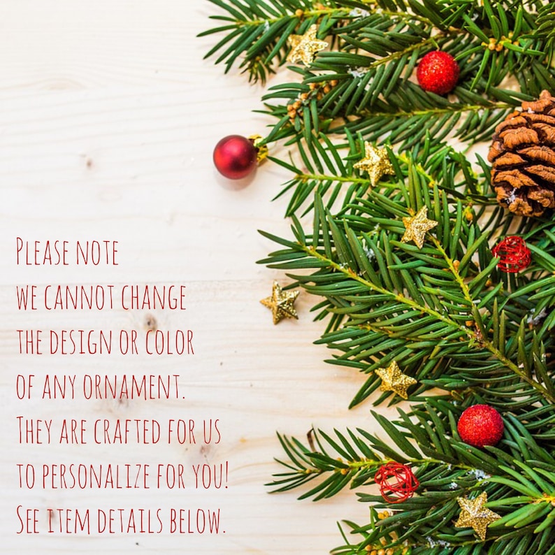 May include: A close-up of a wooden surface with a green pine branch with red and gold ornaments. The text "PLEASE NOTE WE CANNOT CHANGE THE DESIGN OR COLOR OF ANY ORNAMENT. THEY ARE CRAFTED FOR US TO PERSONALIZE FOR YOU! SEE ITEM DETAILS BELOW." is written in red.