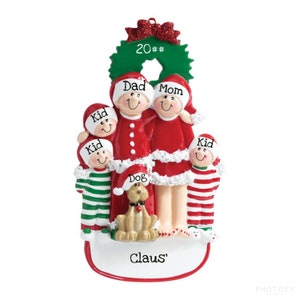 May include: A Christmas ornament featuring a family of five in red and white pajamas, including two children, a dog, and a wreath with the text "20##". The ornament also includes the text "Claus'" at the bottom.