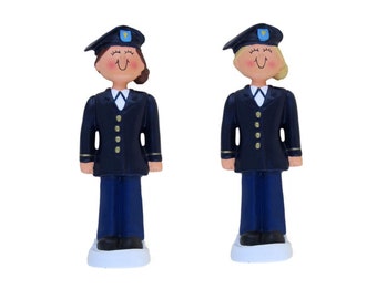 May include: Two figurines of people wearing navy blue uniforms with gold buttons and a blue and gold hat. The figurines are standing on white bases.