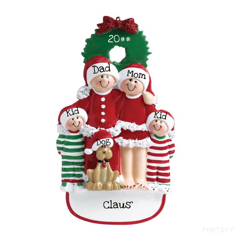 May include: A Christmas ornament featuring a family of four in red and white pajamas with a dog. The ornament is decorated with a green wreath and the text "20##", "Dad", "Mom", "Kid", "Kid", "Dog", and "Claus".