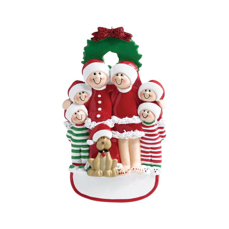 May include: A Christmas ornament featuring a family of five in red and white pajamas with a dog. The family is standing in front of a green wreath with red berries. The ornament has a blank space for personalization.