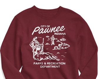 Peut inclure: Un sweat-shirt bordeaux avec un motif blanc. Le motif représente une illustration de style vintage d'une personne chassant un ours avec le texte "City of Pawnee Indiana Parks & Recreation Department".