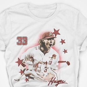 May include: White t-shirt featuring a red and white baseball player graphic. The player is wearing a baseball cap with the letter 'A' on it. The number '33' is printed on the shirt. The text 'Hayes' is printed below the graphic.