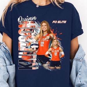 May include: Navy blue t-shirt featuring a volleyball player in an orange jersey with the number 12. The shirt has the text "Quinn" and "FC ELITE" in white and orange. The design includes a volleyball and abstract paint strokes.