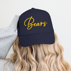 Op de afbeelding: Een donkerblauwe truckercap met een gouden geborduurde tekst die "Bears" zegt.