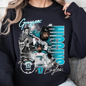 May include: Black sweatshirt featuring a collage of hockey player images. The design includes the name "Greyon Higgins" in a script font, with the name "HIGGINS" in large teal letters. The number "17" is prominent, along with the text "#17 Eagles".