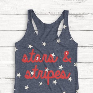 Puede incluir: Un top de tirantes azul marino con un patrón de estrellas blancas y el texto "stars & stripes" en rojo.