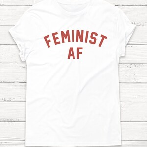 May include: White t-shirt with the text "FEMINIST AF" printed in red.
