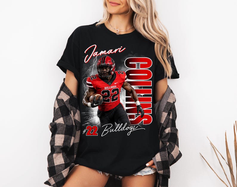 K&ouml;nnte beinhalten: Ein schwarzes T-Shirt mit einem Grafikdruck eines Footballspielers im roten Trikot mit der Nummer 22, dem Namen Jamari Collins und dem Schriftzug Bulldogs. Das Design enth&auml;lt Blitzeffekte sowie eine rote und wei&szlig;e Farbgebung auf der Vorderseite.